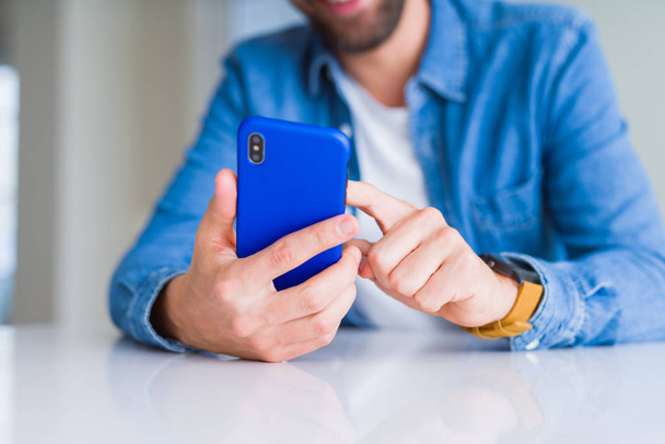 Κοντινό πλάνο του χέρια ο άνθρωπος χρησιμοποιώντας το smartphone και χαμογελαστός - Φωτογραφία, εικόνα