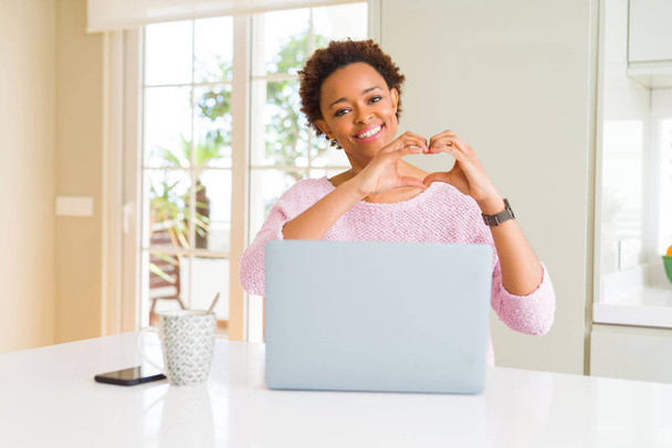 Young african american woman working using computer laptop smiling in love showing heart symbol and shape with hands. Romantic concept. - Foto, Imagem