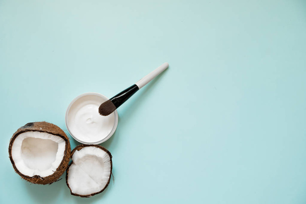 Fresh coconut oil in glassware and wooden spoon on color table background. - Fotoğraf, Görsel