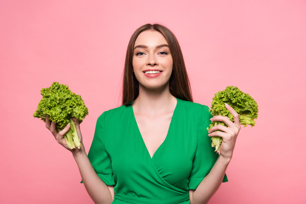 front view of attractive young woman holding lettuce and looking at camera isolated on pink - Photo, Image