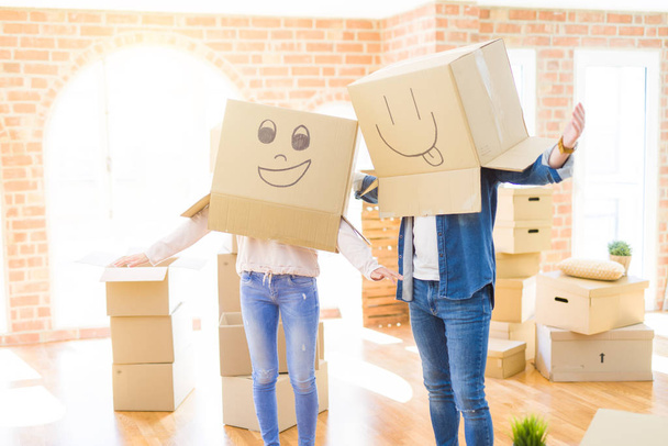 Couple having fun at new apartment wearing boxes with funny face - Foto, afbeelding