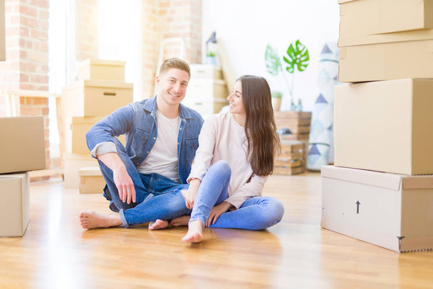 Young beautiful couple relaxing sitting on the floor around card - Photo, Image