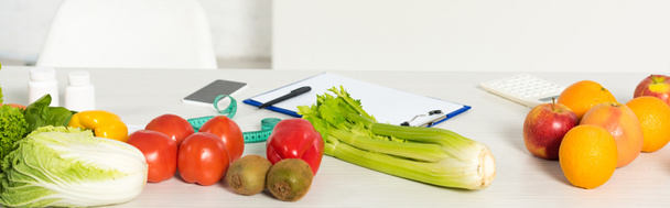 colpo panoramico di frutta e verdura fresca, metro a nastro, appunti, penna, calcolatrice e smartphone con schermo bianco sul tavolo
 - Foto, immagini