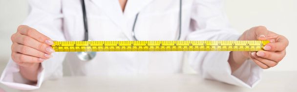 panoramic shot of dietitian in white coat with stethoscope holding measure tape - Photo, Image
