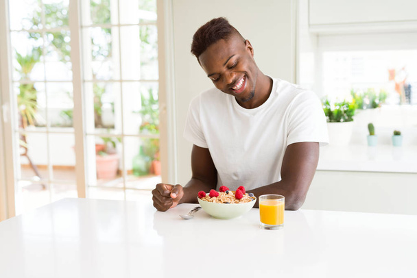 schöner afrikanisch-amerikanischer Mann isst hitziges Getreide und Beeren - Foto, Bild