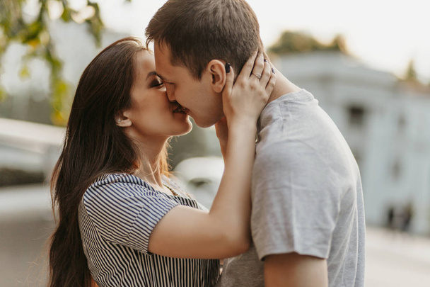 Happy young couple in love teenagers friends dressed in casual style kissing at street - Photo, Image
