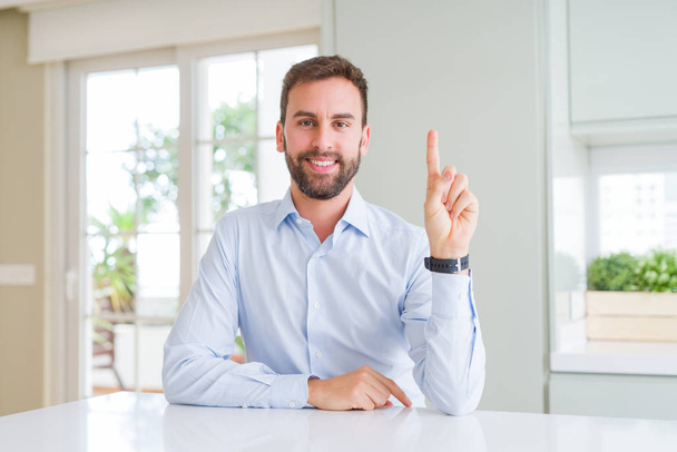 Hombre de negocios guapo mostrando y señalando con el dedo número uno mientras sonríe confiado y feliz
. - Foto, imagen