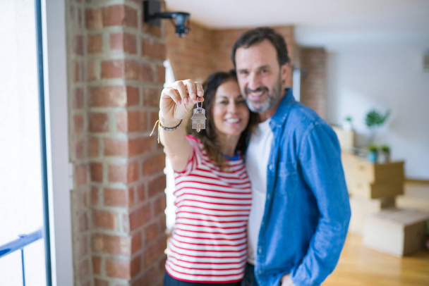 Μέση ηλικία γηραιότερος ρομαντικό ζευγάρι κρατώντας και δείχνοντας τα κλειδιά του σπιτιού - Φωτογραφία, εικόνα