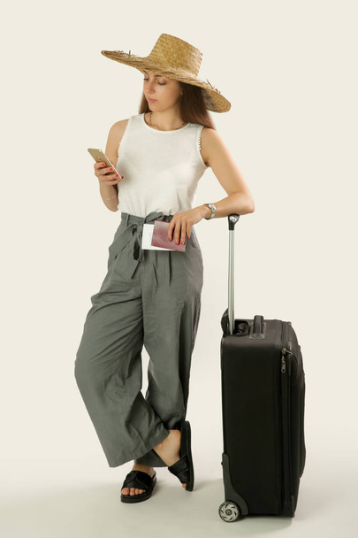 Jeune voyageur regardant le téléphone. Femme avec bagages, prise de vue en studio. Concept vacances d'été
. - Photo, image