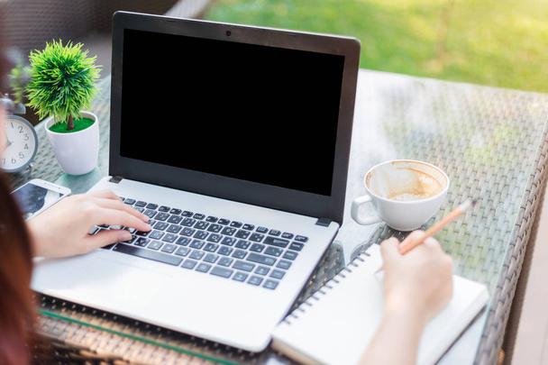 Κοντινό-up επιχείρηση θηλυκό δουλεύοντας με το laptop κάνει ένα σημείωμα και ala - Φωτογραφία, εικόνα
