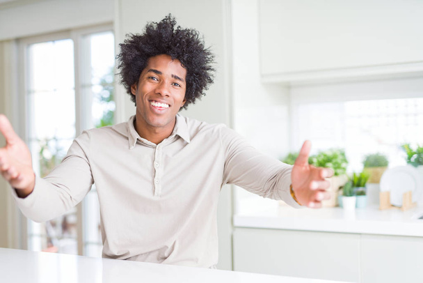 Američan Afričana muž doma při pohledu na kameru s otevřenou náručí objetí úsměvem. Veselý výraz zahrnující štěstí. - Fotografie, Obrázek