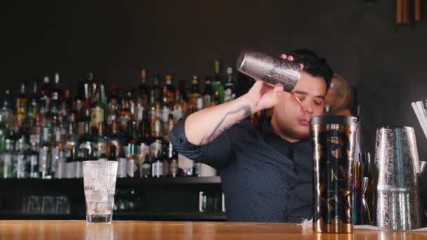 Jovem barman profissional derrama um copo de líquido em uma coqueteleira
 - Filmagem, Vídeo
