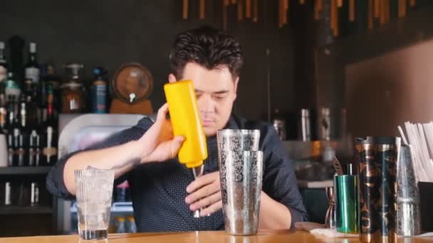 Jovem barman profissional efetivamente derrama líquido de uma garrafa amarela em uma coqueteleira
 - Filmagem, Vídeo