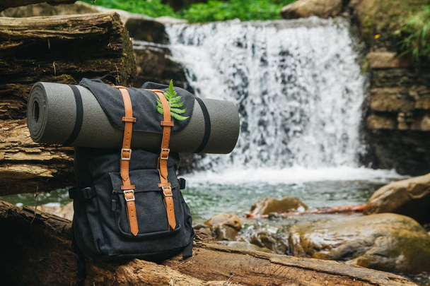 Hipster stopař Turistický batoh na pozadí řeky a vodopádu, poutník relaxační koncept, cestování dobrodružstvím. - Fotografie, Obrázek