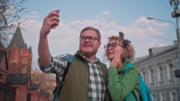 Young, beautiful couple, makes selfie in the old town. Young Finnish family travels. Friends take pictures of themselves on the phone. Tourists fool around at the camera. - Footage, Video
