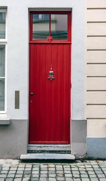 Vintage kırmızı ön kapı Bruges, Belçika'da çekilen Noel ağacı süsü ile dekore edilmiştir. Üst kısmında pencere ile eski kırmızı kapı. - Fotoğraf, Görsel