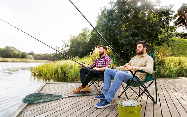male friends fishing and drinking beer on lake - Fotó, kép
