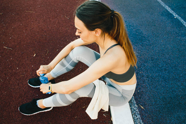 Mulher bonita sentada no chão com uma garrafa de água depois de Jogging ao ar livre
 - Foto, Imagem