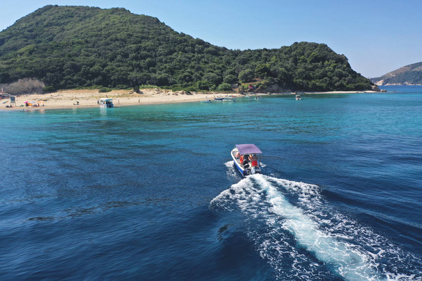 Mała łódź z turystami pozycji do słynnej małej bezludnej wyspie Marathonisi featuring krystalicznie czyste wody brzeg i naturalną wylęgarni z Caretta-Caretta żółwi morskich, Wyspa Zakintos, Jońskie, Greec - Zdjęcie, obraz