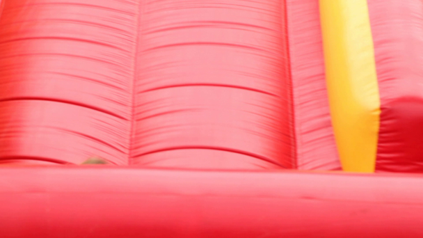 Chico y chica se van con grandes toboganes de goma inflables rojos
 - Imágenes, Vídeo