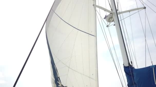 Bílé plachty vlající ve větru pohybující se jachty na pozadí modré oblohy během plavby po moři. Jachting jako relaxace aktivní životní styl. - Záběry, video