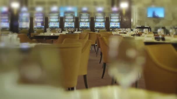 Empty tables with wine glasses in restaurant near slot machines in casino - Footage, Video