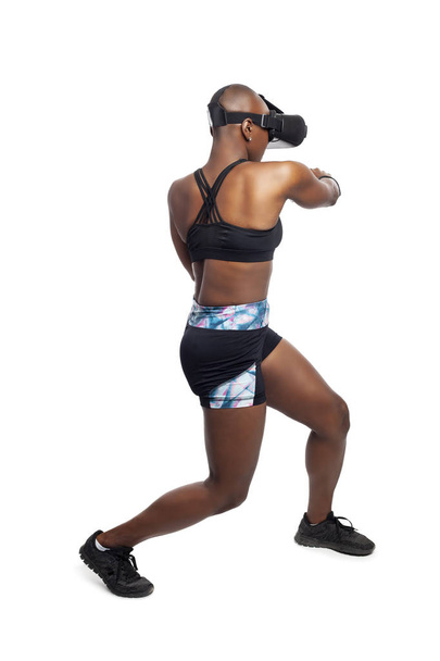 Athletic black female gamer playing video games and exercising while wearing a virtual reality headset.  She is punching like she is boxing or fighting.  Depicts wearable technology and healthy activities.  - Foto, immagini