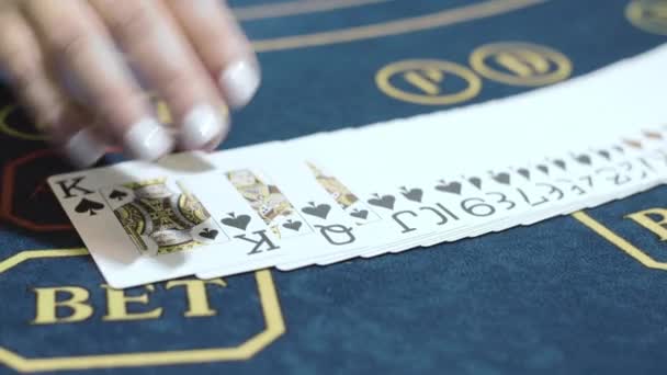 Nő krupié csoszogó kártyák előtt pókerrel közelről. Kaszinó-kereskedő - Felvétel, videó