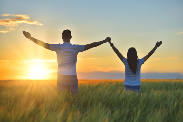 Young couple feeling free in a beautiful natural setting, in what field at sunset - Photo, image