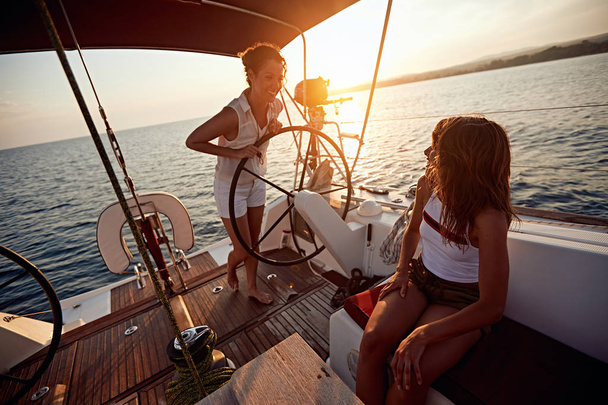 young women sailing on the luxury boat together and enjoy at sunet - Fotografie, Obrázek