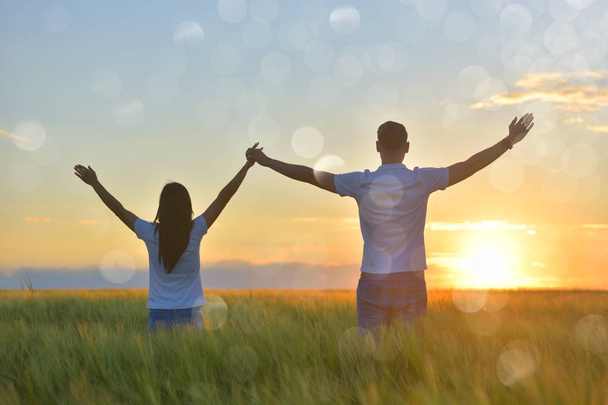 Young couple feeling free in a beautiful natural setting, in what field at sunset - Foto, afbeelding