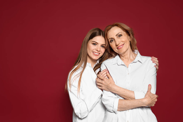Portret van gelukkige moeder met haar dochter op kleur achtergrond - Foto, afbeelding