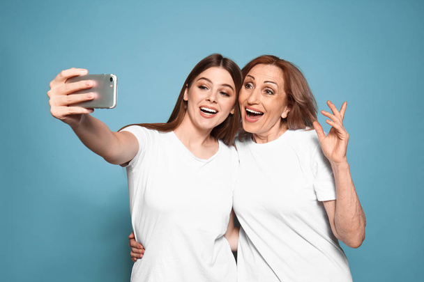 Portrait de mère heureuse avec sa fille prenant selfie sur fond de couleur
 - Photo, image