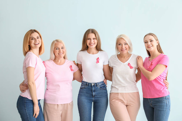 Hermosas mujeres de diferentes edades con cintas de color rosa sobre fondo claro. Concepto de cáncer de mama
 - Foto, imagen