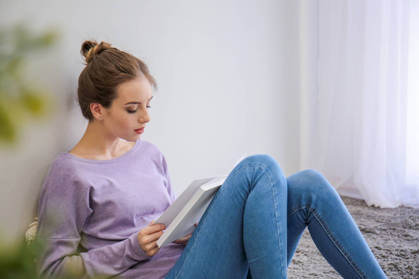 Beautiful young woman reading book at home - Foto, imagen