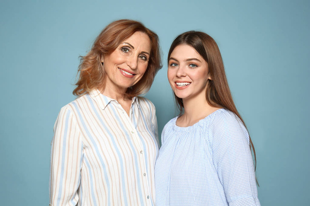 Portret van gelukkige moeder met haar dochter op kleur achtergrond - Foto, afbeelding