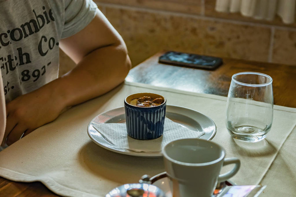 Bule de metal pequeno com saco de chá, alguns óculos na mesa do restaurante. Vapor branco sobe acima da água quente.. Foco seletivo
 - Foto, Imagem