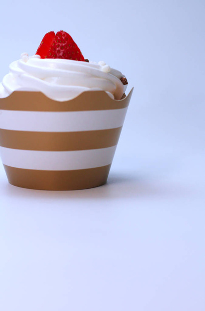 Lähikuva cupcake kermavaahtoa koristeltu tuoretta mansikkaa ja suklaata pallot valkoisella pohjalla. Eristetään
 - Valokuva, kuva