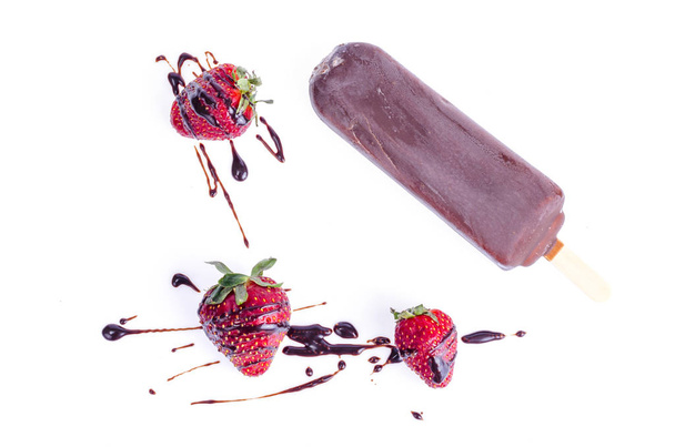 Jäätelö suklaakuorrutuksessa kiinni mansikoilla ja mintulla
 - Valokuva, kuva