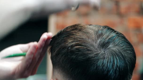 Barber cutting man with scissors under comb. Man having hair cut in barbershop - Felvétel, videó