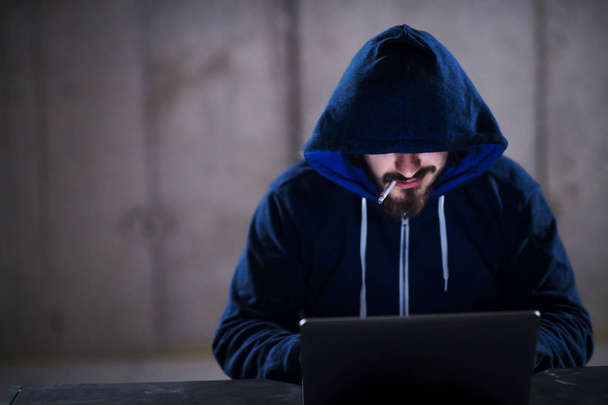 young hacker using laptop computer while working in dark office - Valokuva, kuva