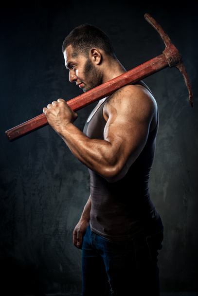 Muscular man holding pickaxe - Zdjęcie, obraz