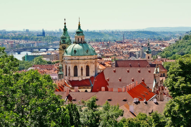 Dome and Bell tower of Saint Nicholas cathedral in scene of Vltava river and bridge in Prague city, Prague (Praha), Czech Republic (Ceska Republika), Bohemia region - Photo, Image