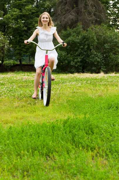 Young beautiful woman cycling in the park - Fotó, kép
