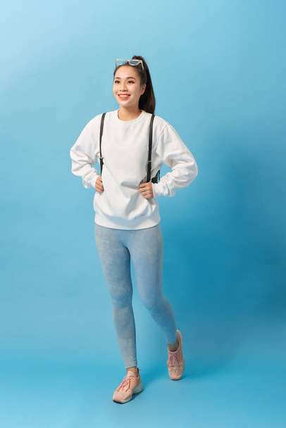 Full length photo of asian woman student walking with backpack isolated over light blue background - Photo, image