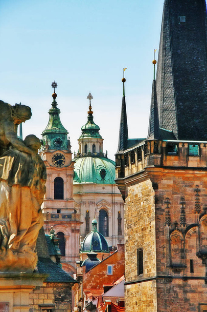 Dome and Bell tower of Saint Nicholas cathedral with medieval tower of Charles bridge on the side of Lesser Town in Prague (Praha), Czech Republic (Ceska Republika), Bohemia region - Photo, Image