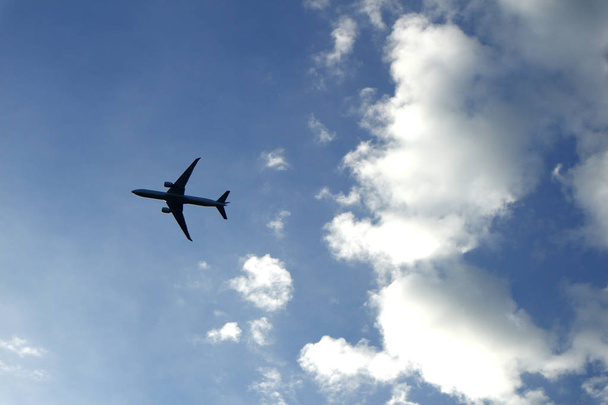 Αεροπλάνο που πετάει και καθαρός γαλάζιος ουρανός με λευκά σύννεφα - Φωτογραφία, εικόνα