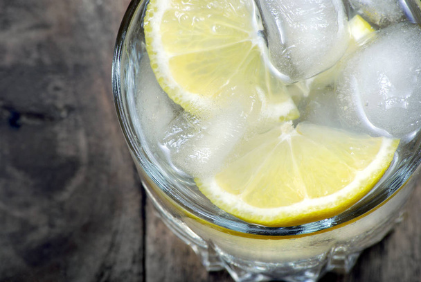 glasses of cold water with ice and lemon on a wooden table. close up. top view - Fotografie, Obrázek