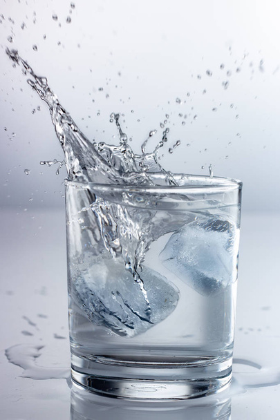 spuitwater in een glas op een grijze achtergrond - Foto, afbeelding