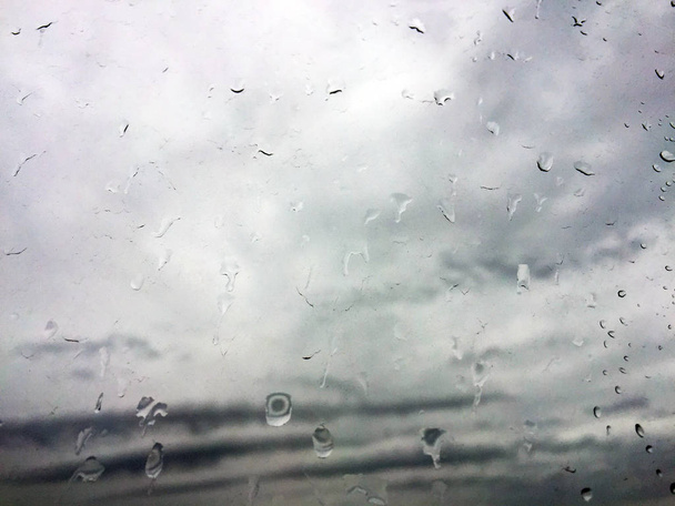 グラスの上の雨から落ちる。窓の外の雲. - 写真・画像